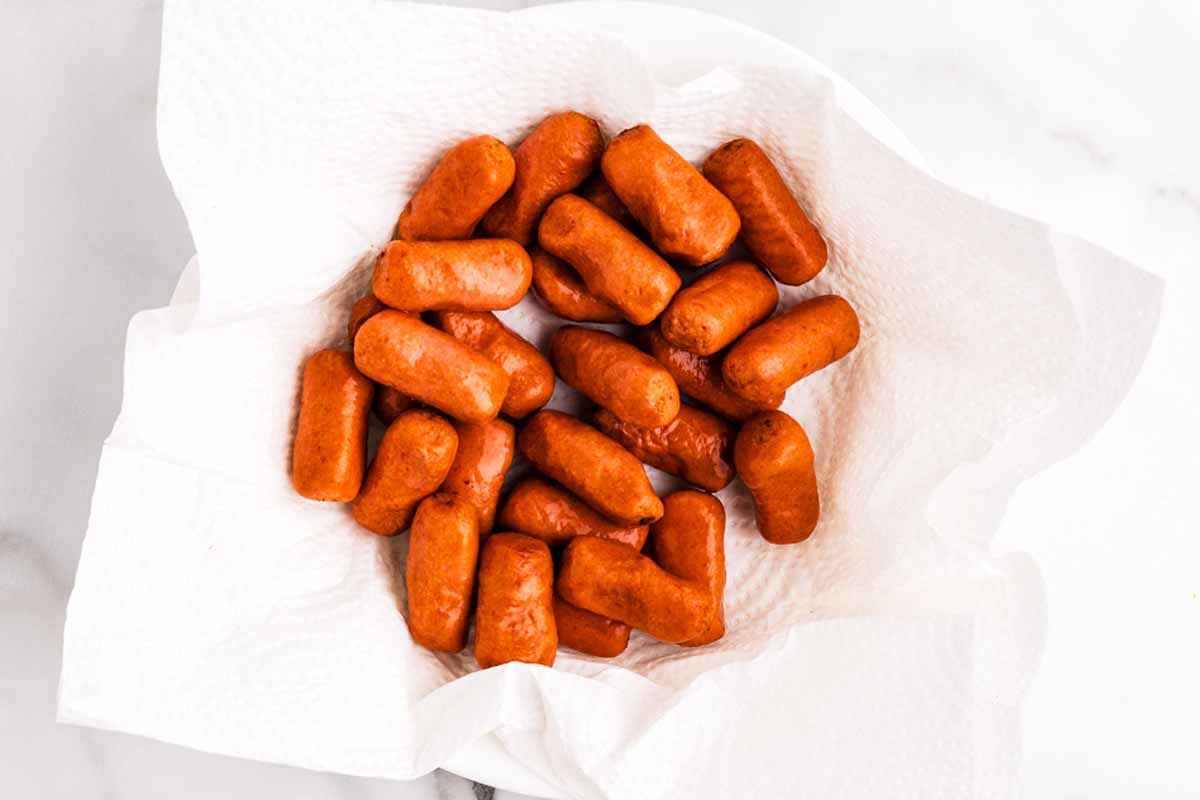 Dried cocktail sausages on paper towels.