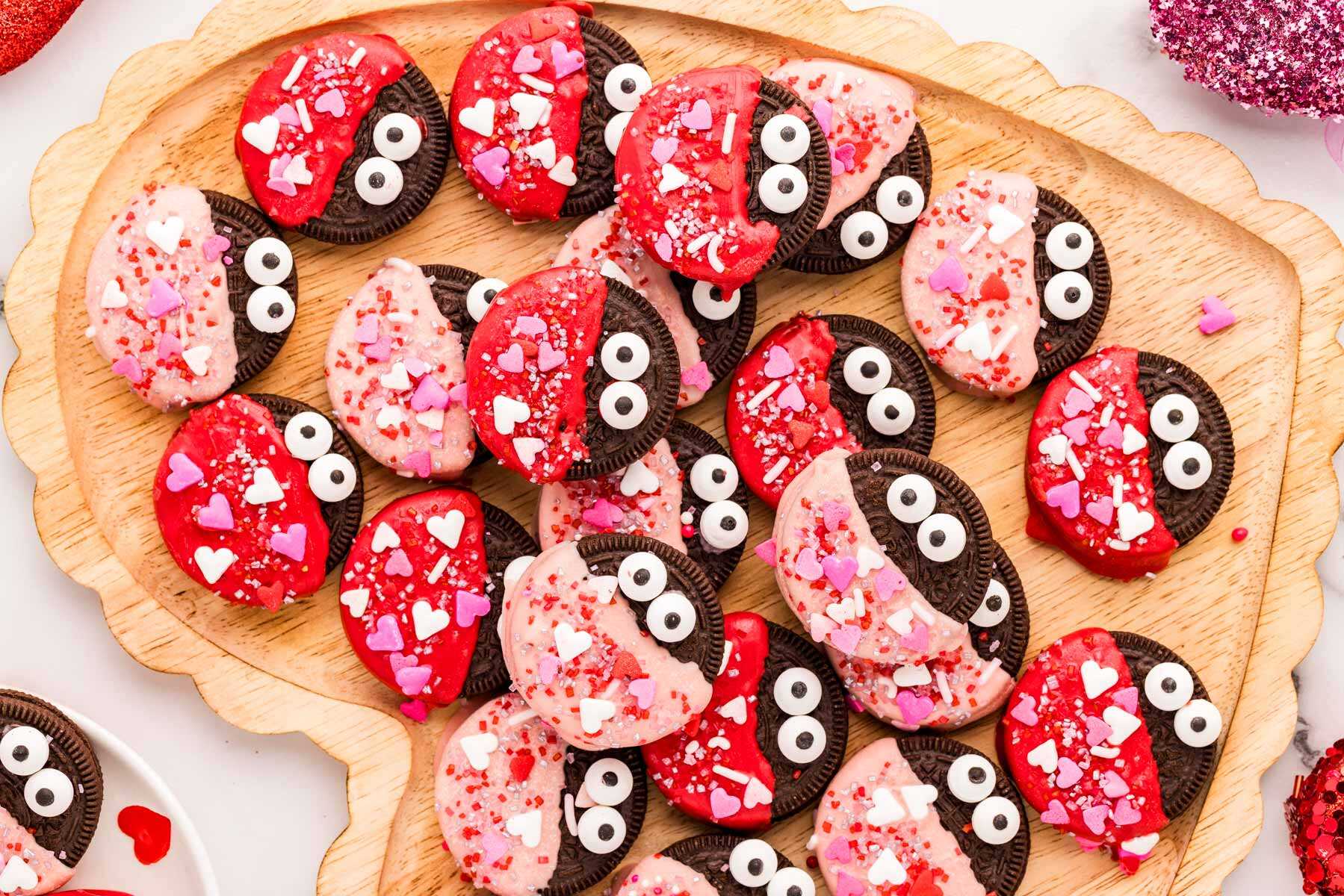 Love bug decorated Oreos on a wooden heart-shaped tray.