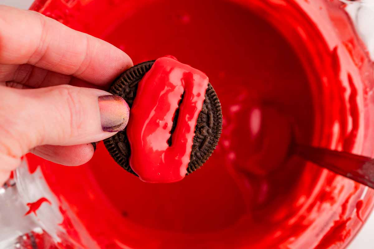 drizzling red candy melt over an Oreo cookie.