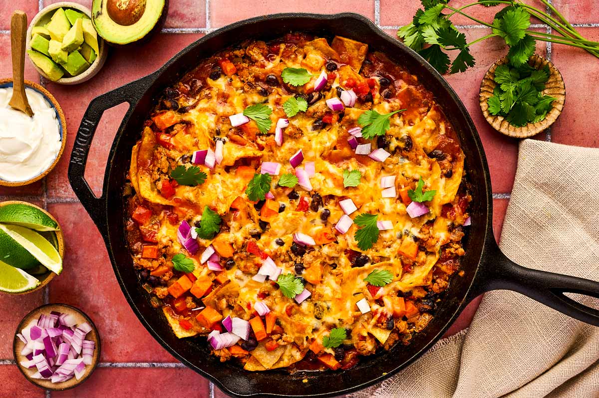 Enchilada Casserole being served from a cast iron skillet.