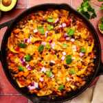 Enchilada Casserole being served from a cast iron skillet.