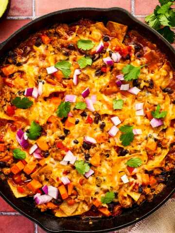 Enchilada Casserole being served from a cast iron skillet.