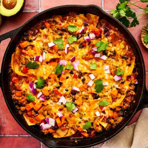 Enchilada Casserole being served from a cast iron skillet.