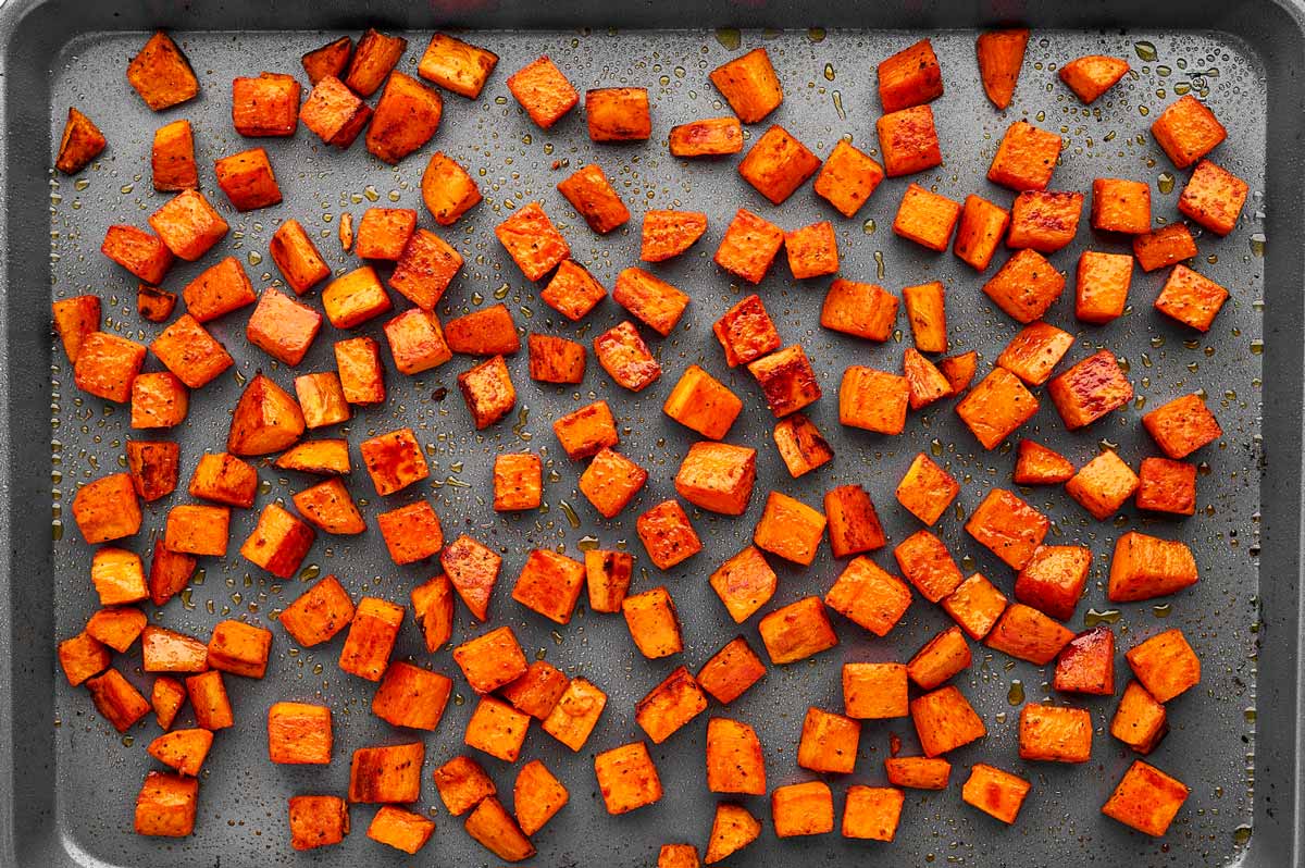 Roasted sweet potato cubes on a pan.