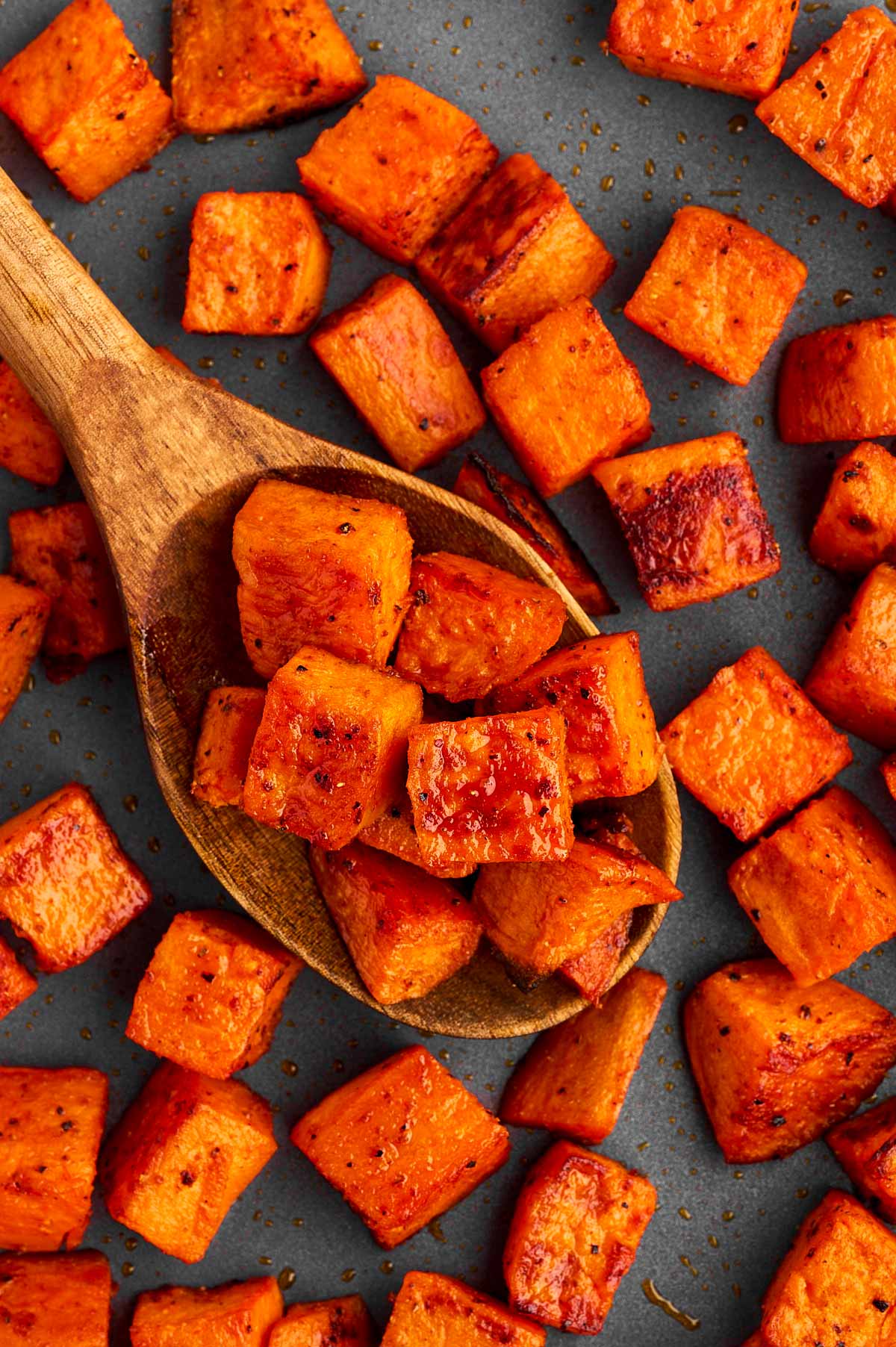 Spoon with roasted sweet potato cubes.