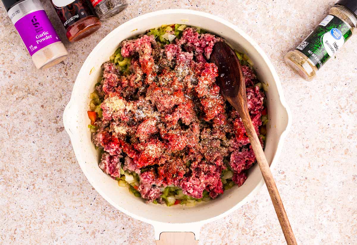 Cooked vegetables and raw ground beef in skillet.
