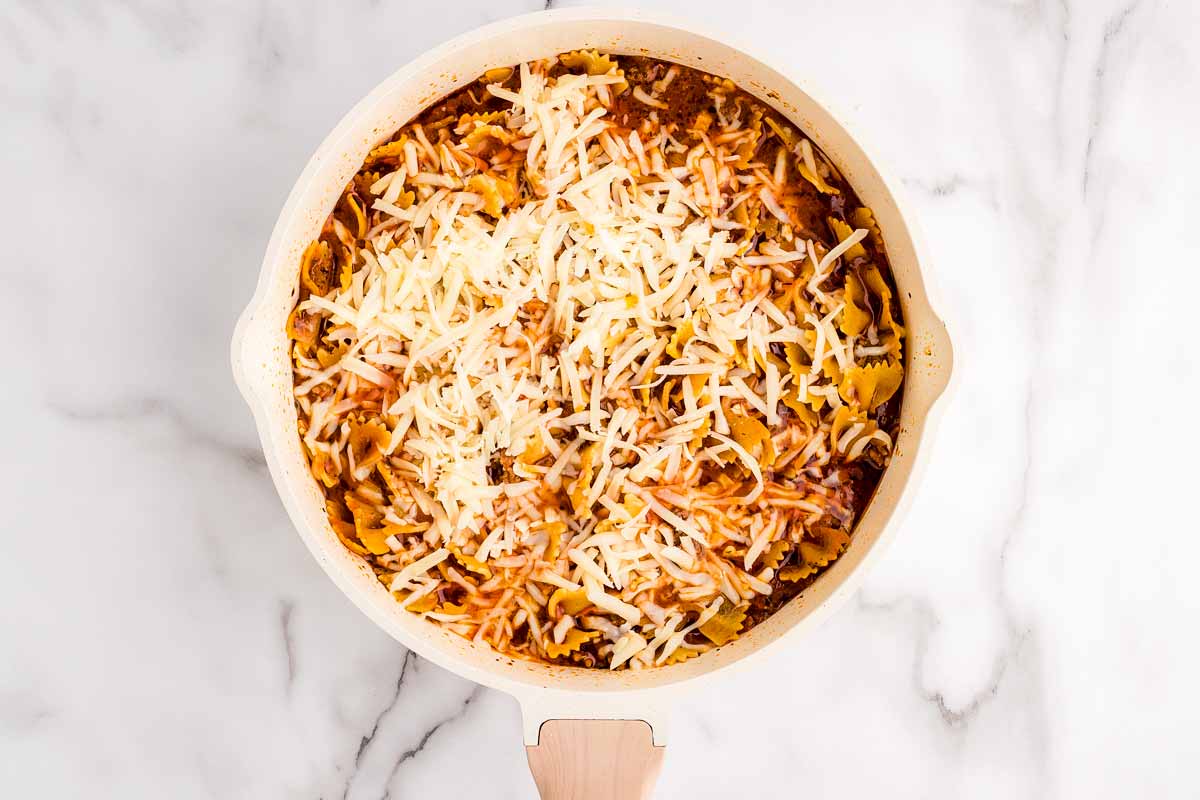Adding cheese to skillet lasagna.