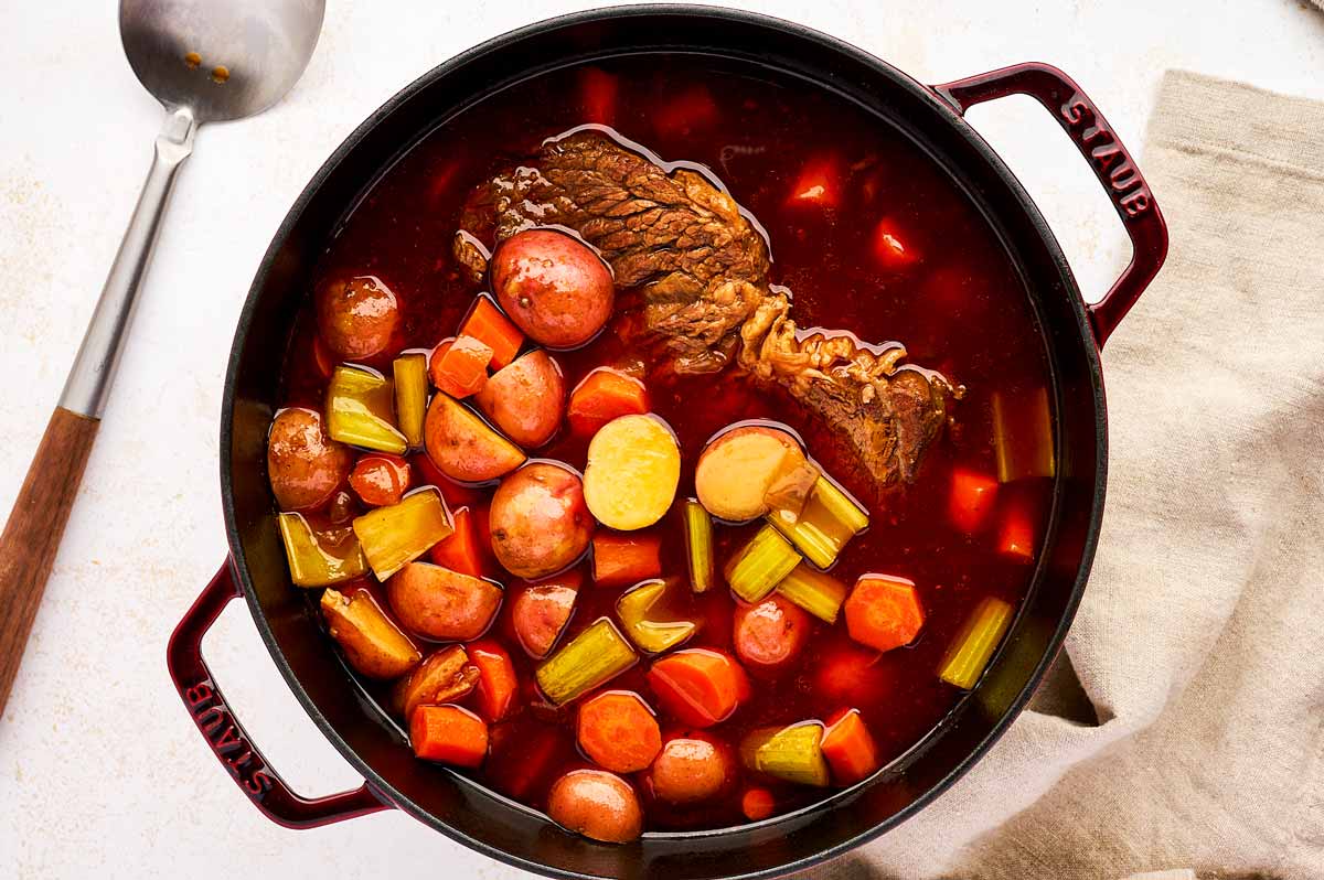 Adding potatoes, carrots and celery to chuck roast.