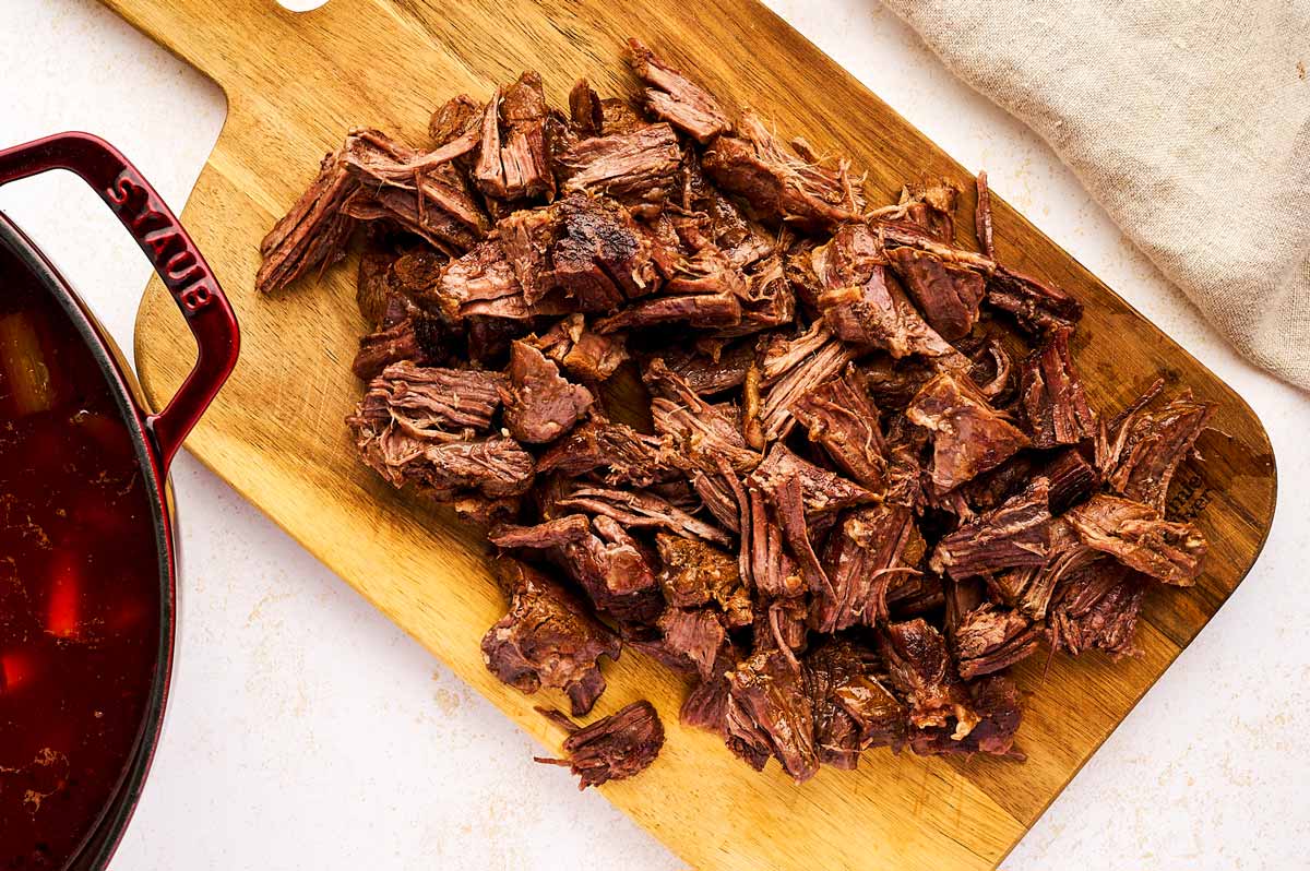 Shredded beef on wooden cutting board.