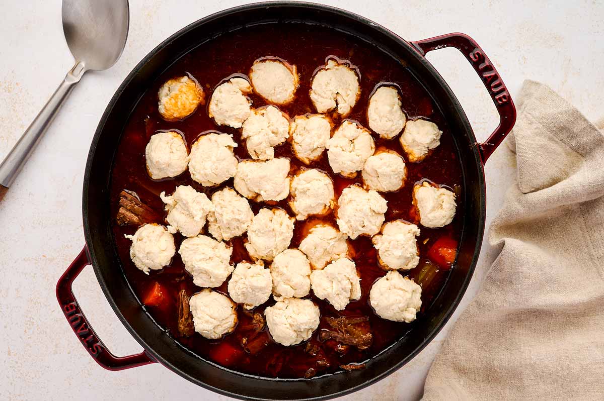 Uncooked dumplings on top of beef stew.
