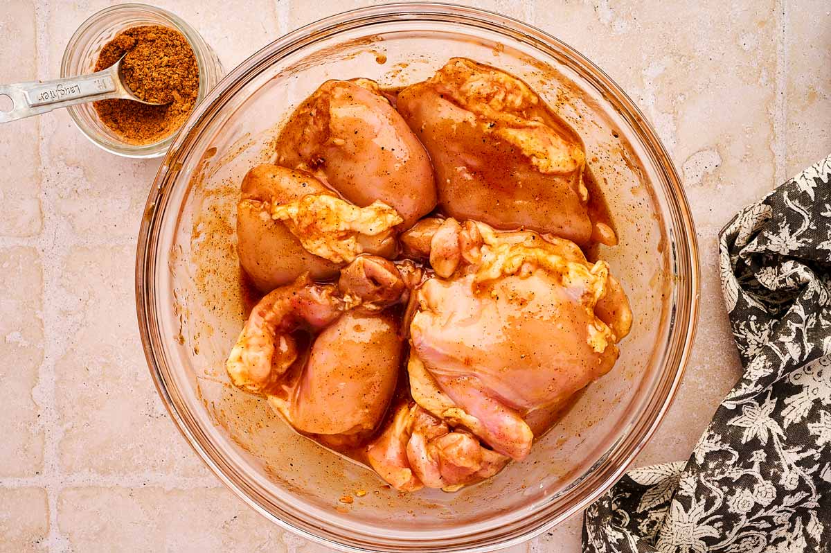 Marinating chicken thighs in a glass bowl.