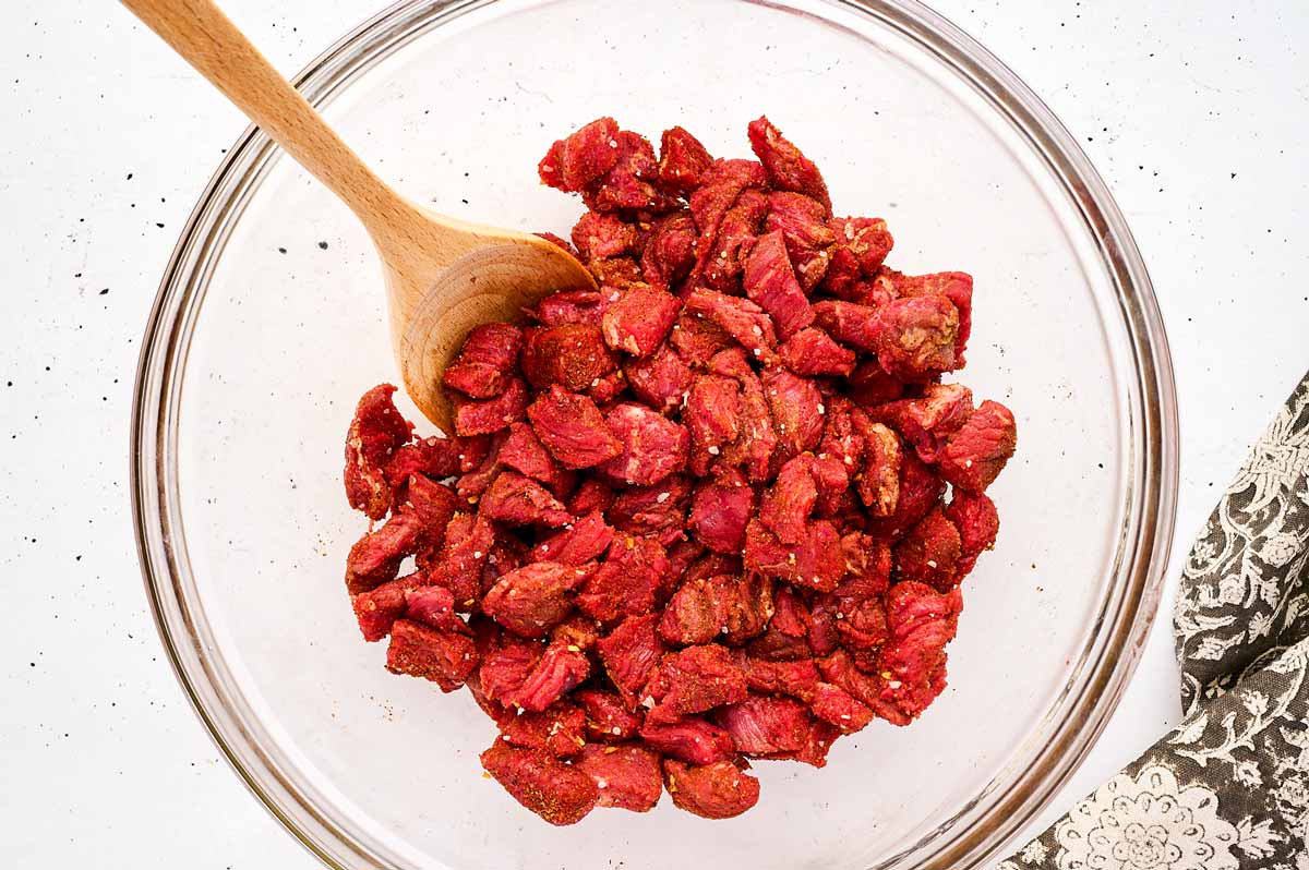 Cut steak with spices in a bowl.