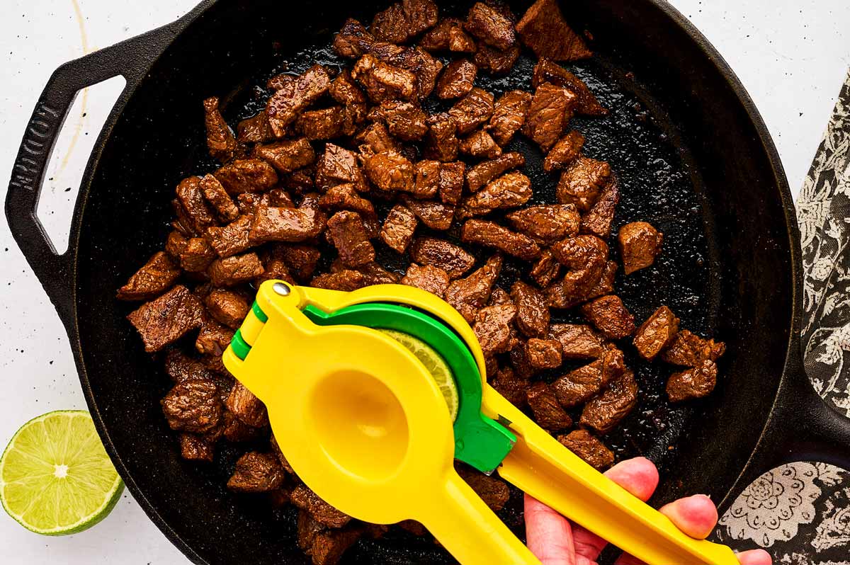 Squeezing lime over seared steak pieces.