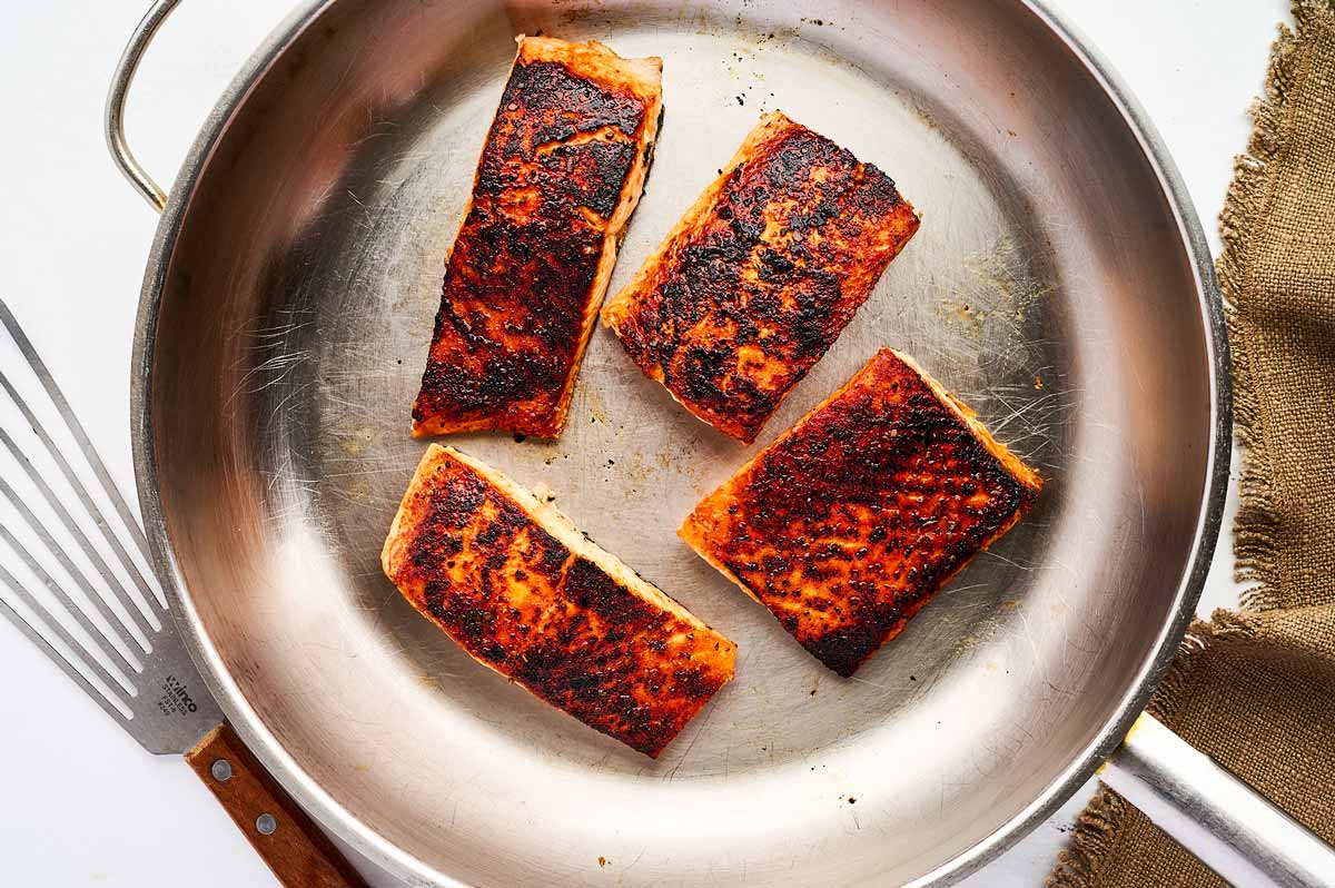 Seared salmon pieces in skillet.
