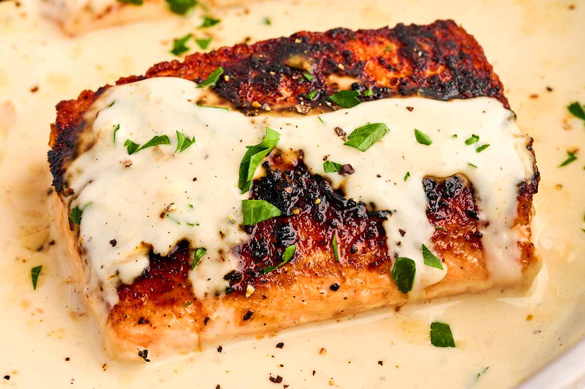 Piece of salmon with creamy dijon sauce and chopped parsley.
