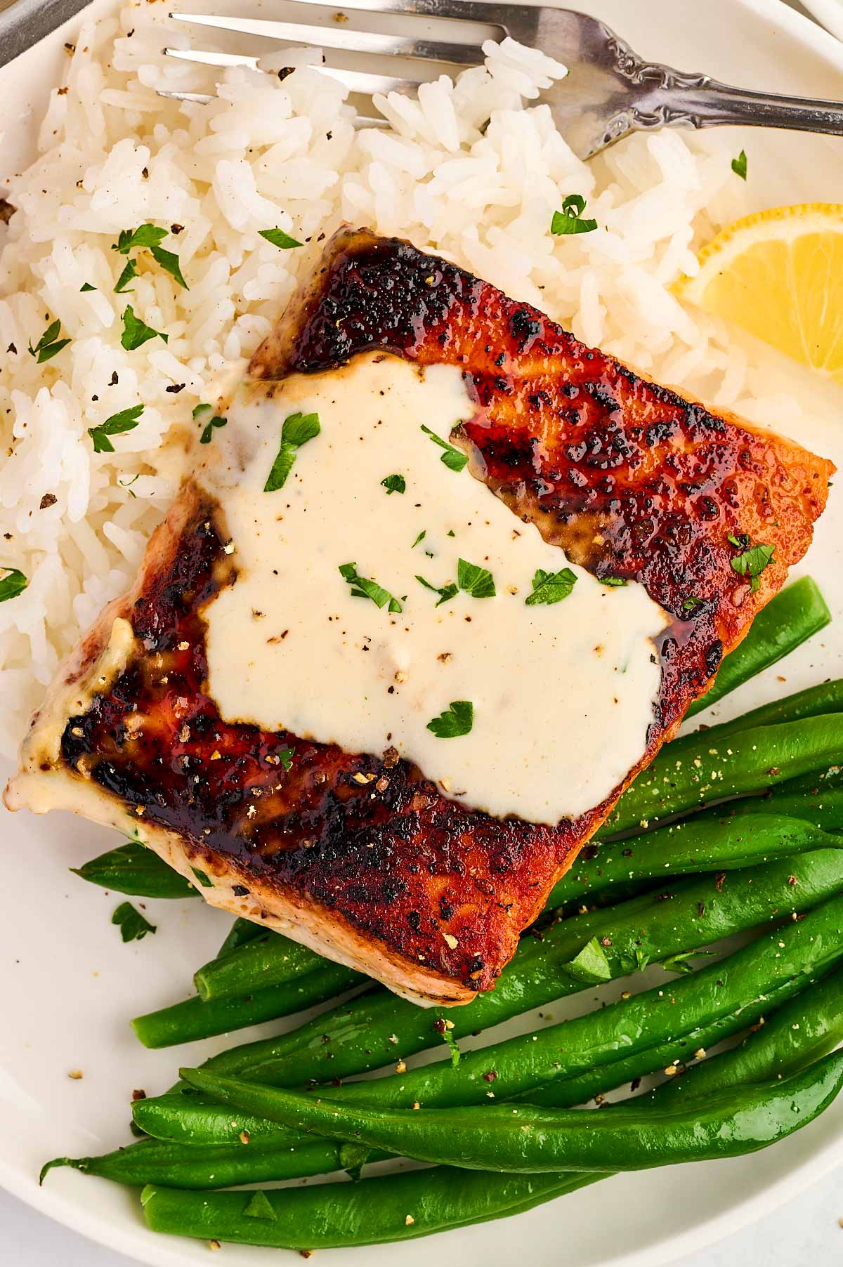 Piece of salmon with creamy dijon sauce on a plate.