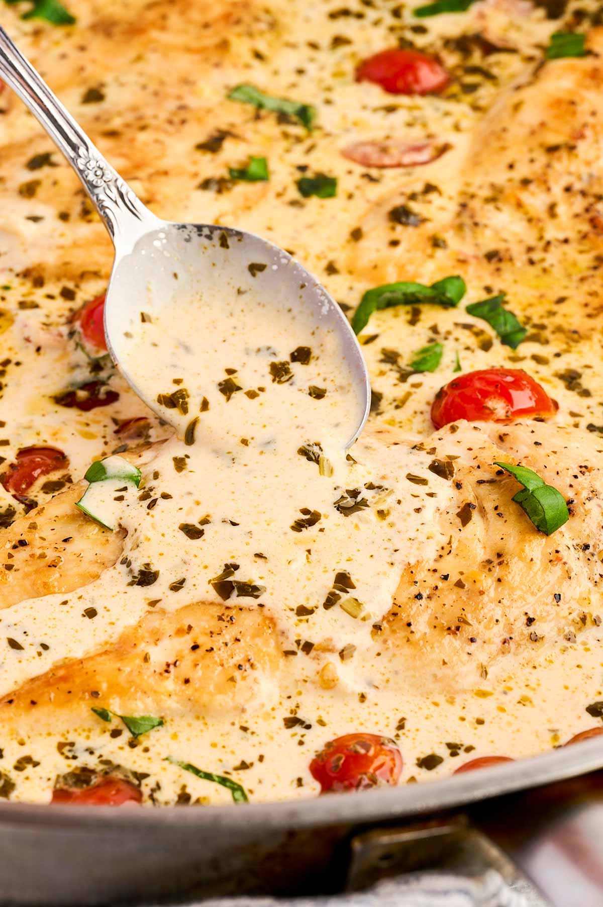 Spooning sauce over pesto chicken.