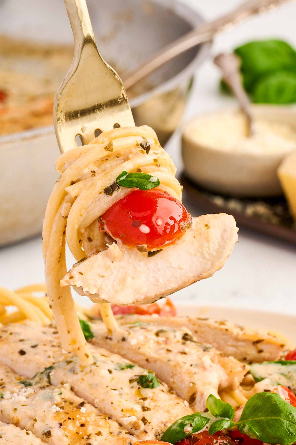 Spaghetti, chicken and tomato on fork.