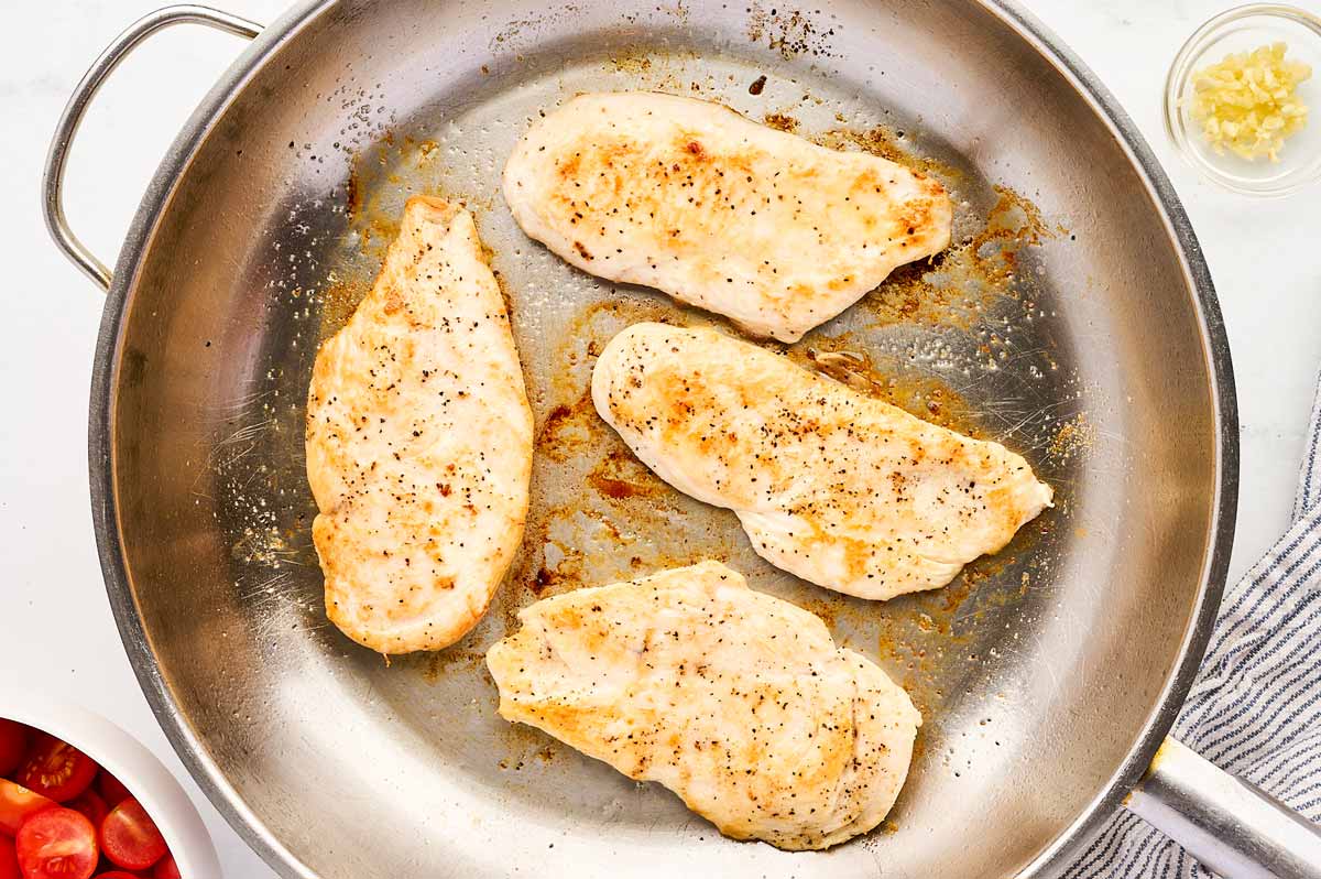 Searing chicken in a skillet.