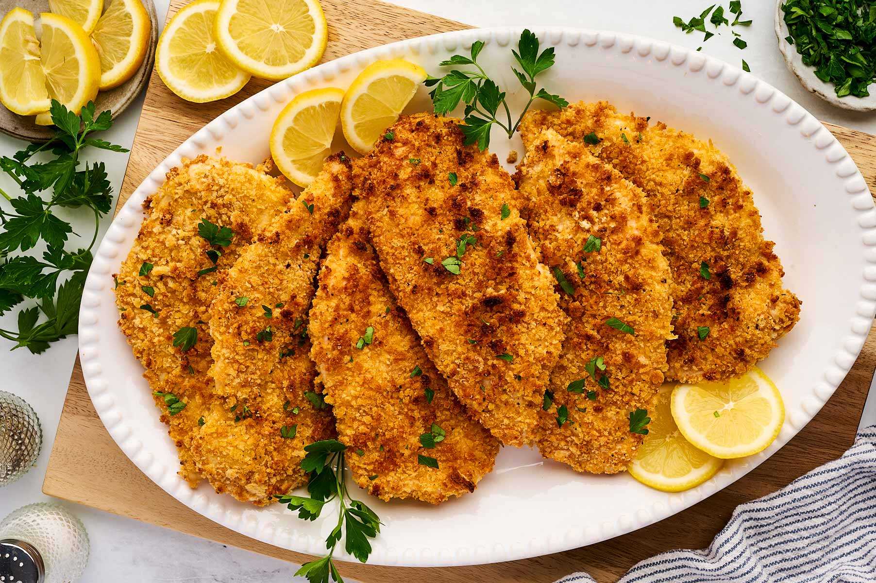 Crispy baked chicken cutlets on a white platter.