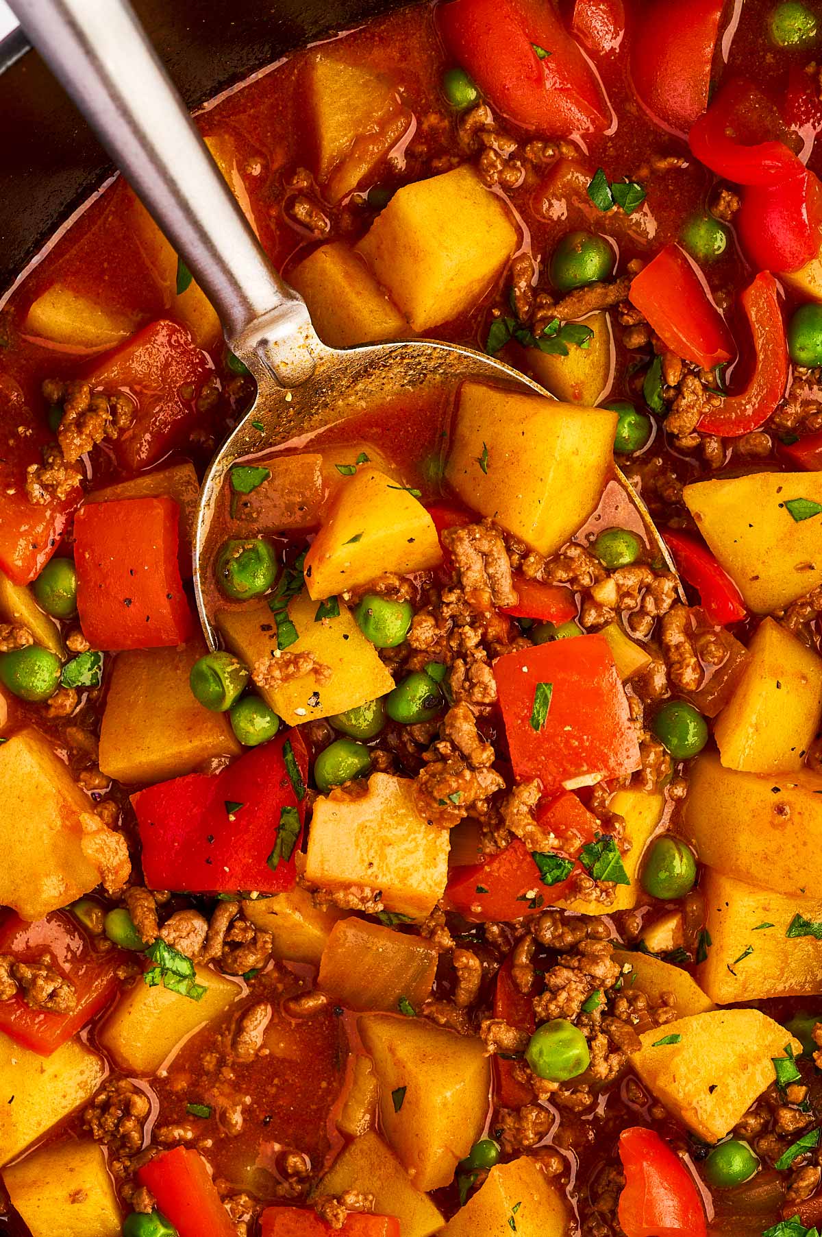 Close up of a spoon in one pot ground beef and potatoes.
