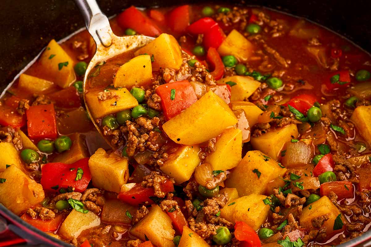 Close up view of serving ground beef and potatoes with a large spoon.