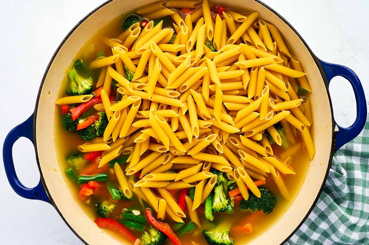 Uncooked pasta primavera in pan.