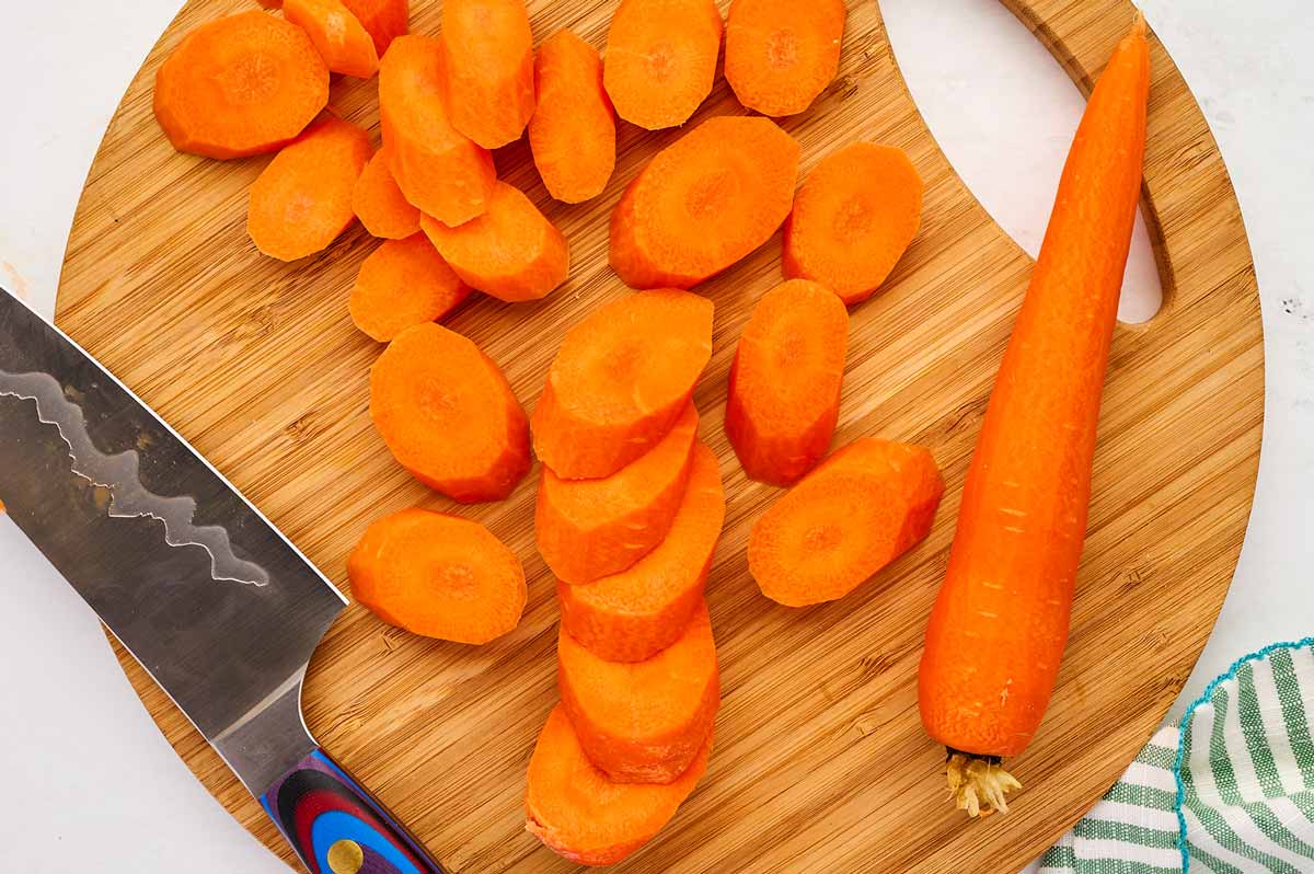 Sliced carrots on a wooden cutting board.