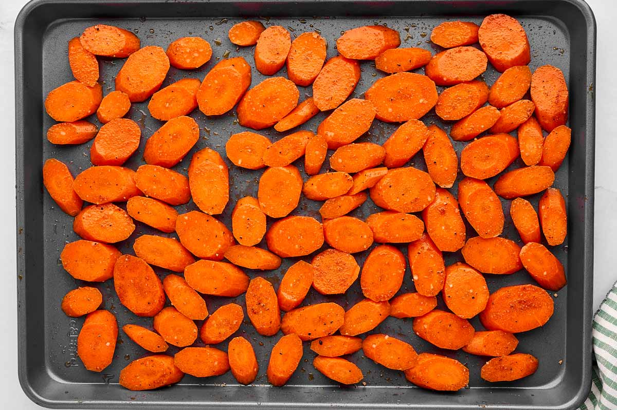 Seasoned sliced carrots on sheet pan.