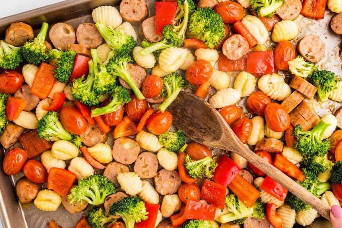 Stirring sheet pan gnocchi with a wooden spoon.