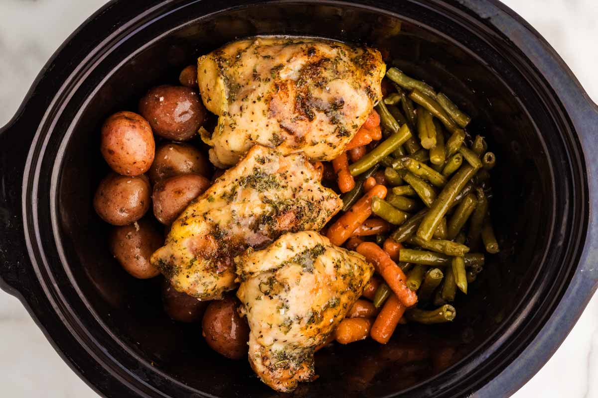 Slow cooker with chicken thighs and vegetables.