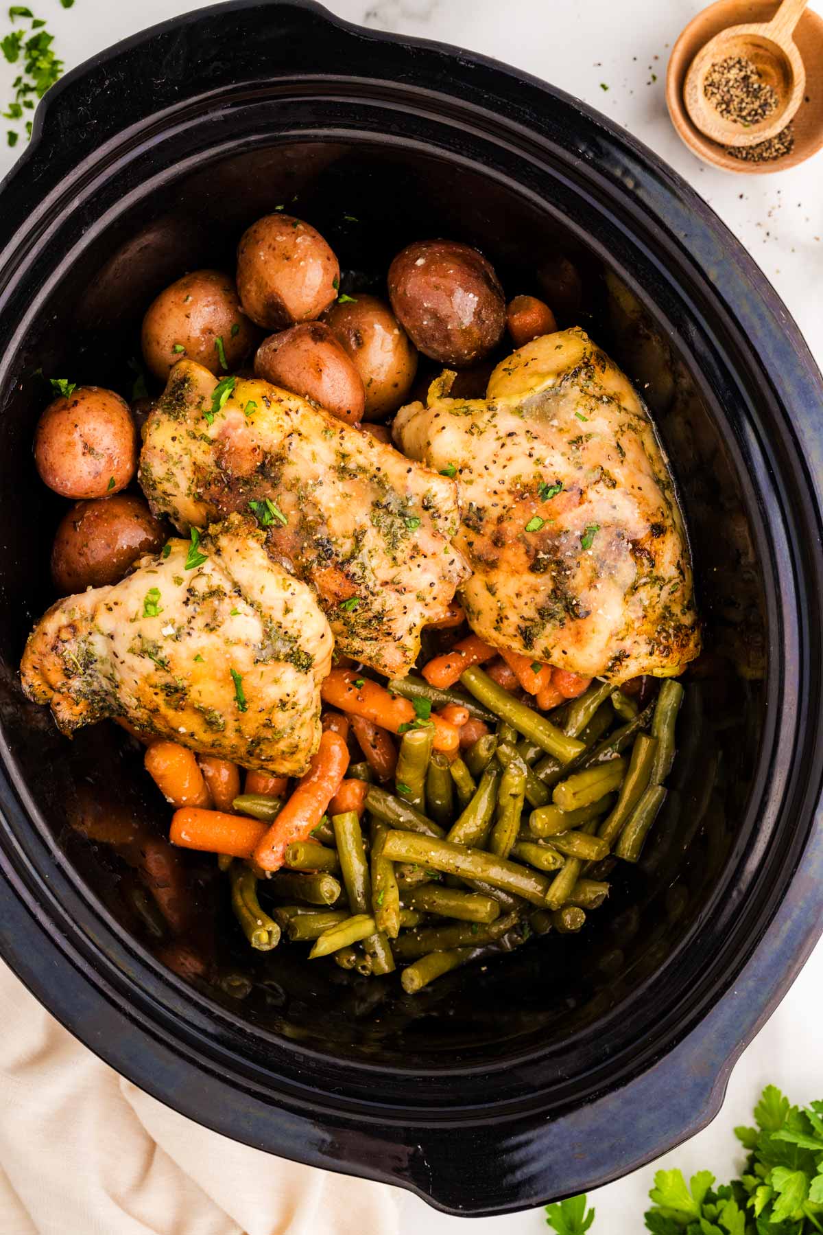 Slow cooker with chicken and vegetables in garlic butter sauce.