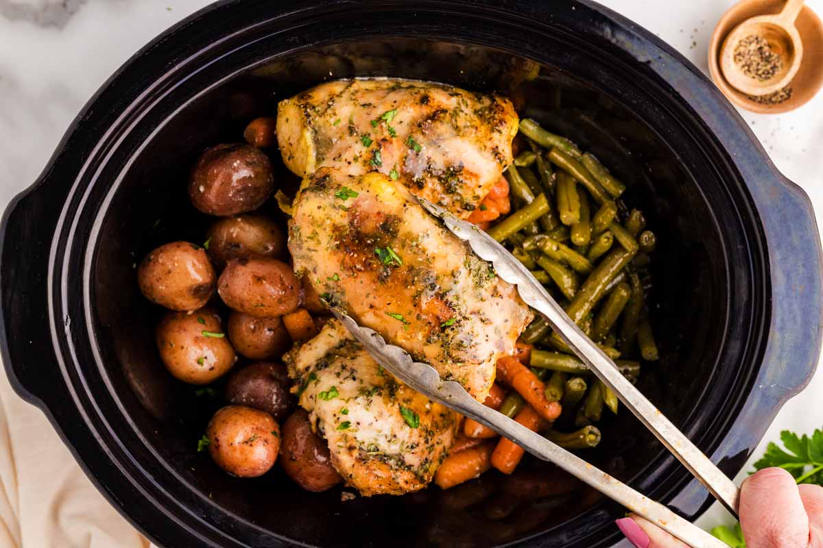 Slow cooker with chicken thighs and vegetables.