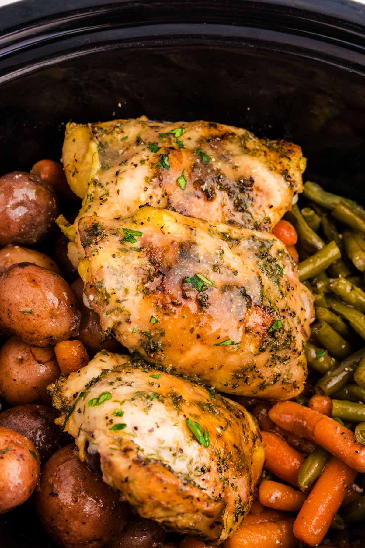 Close up photo of garlic butter chicken thighs in slow cooker.