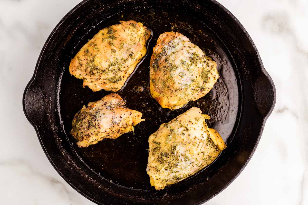 Chicken thighs in cast iron skillet.