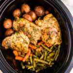 Slow cooker with chicken and vegetables in garlic butter sauce.
