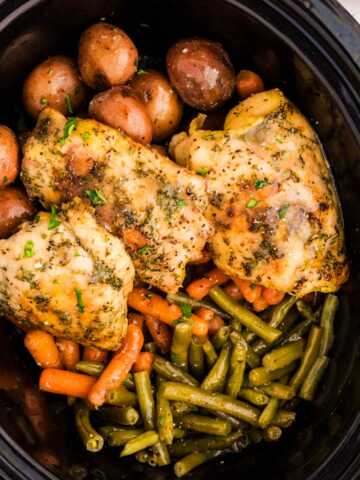 Slow cooker with chicken and vegetables in garlic butter sauce.