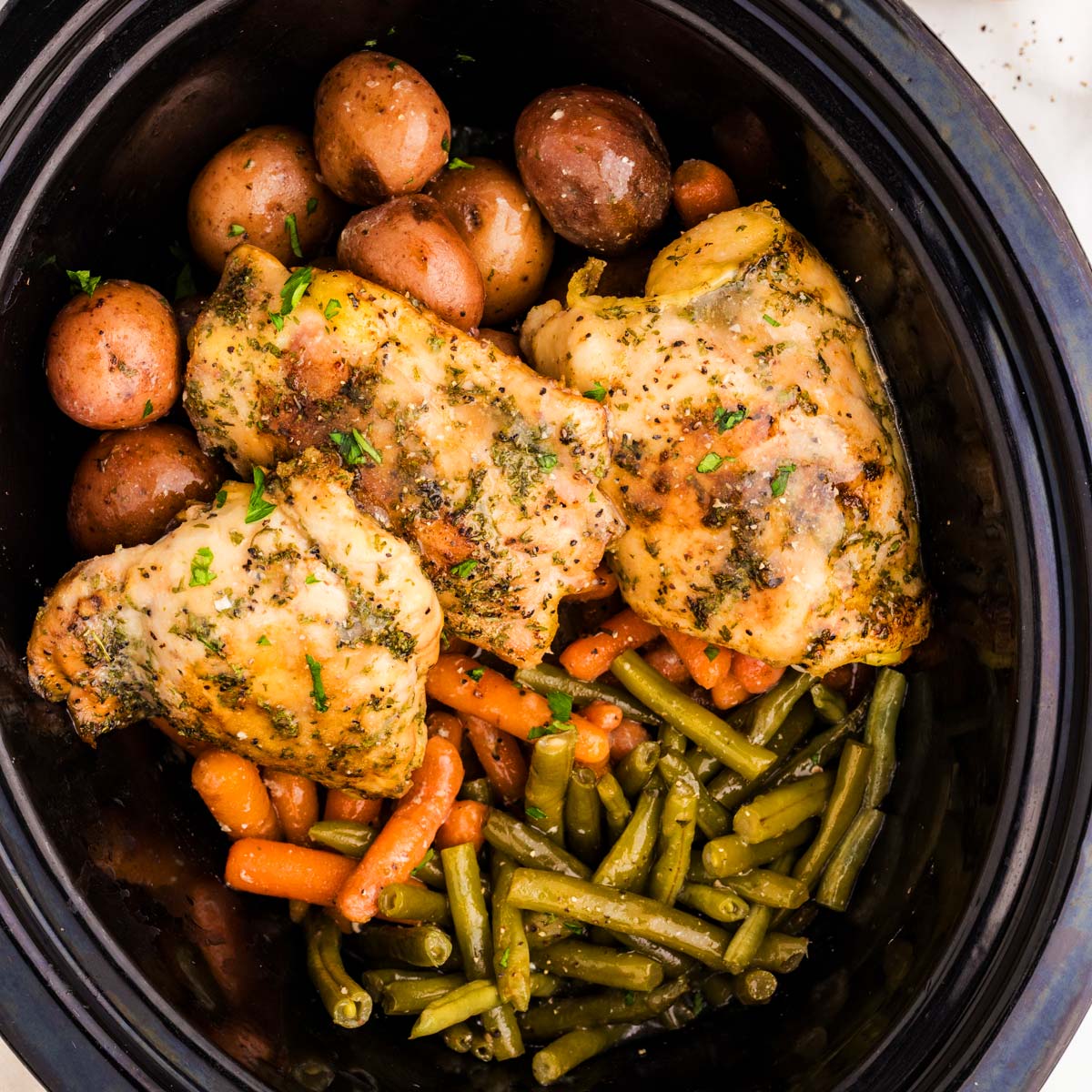 Slow cooker with chicken and vegetables in garlic butter sauce.
