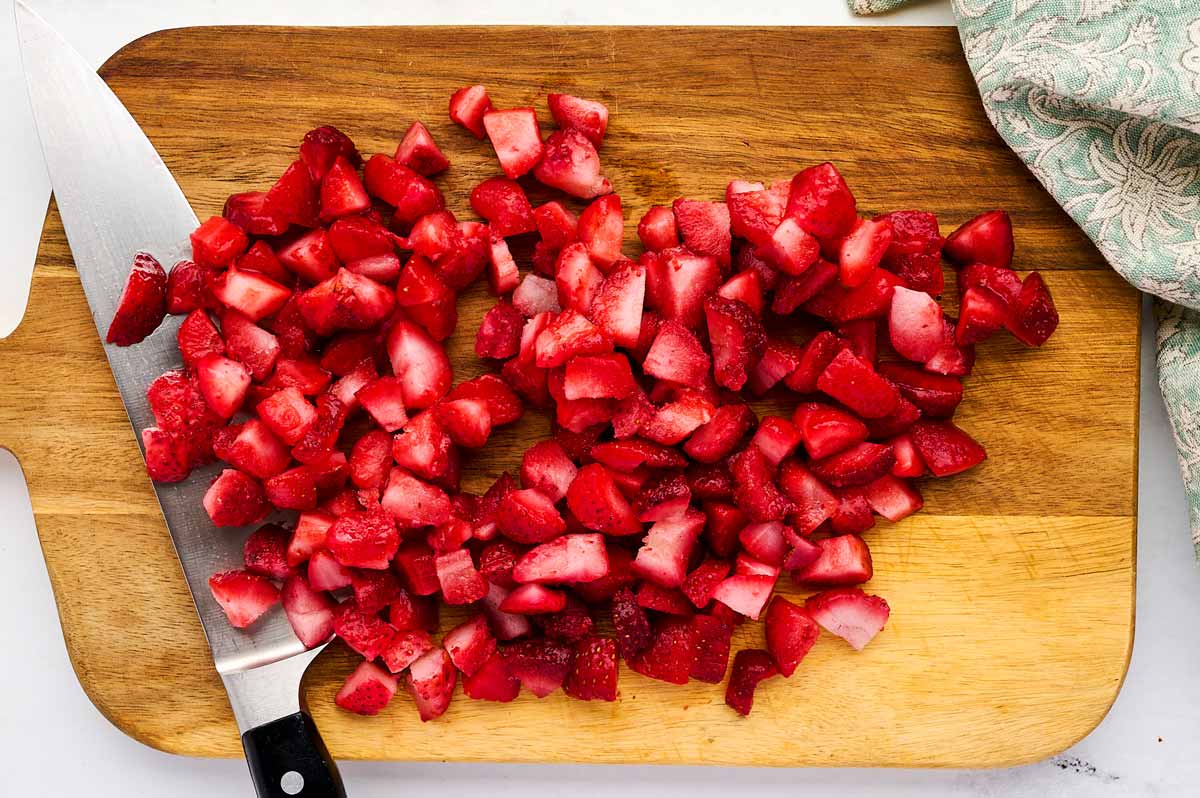 Diced strawberries on a wooden board.