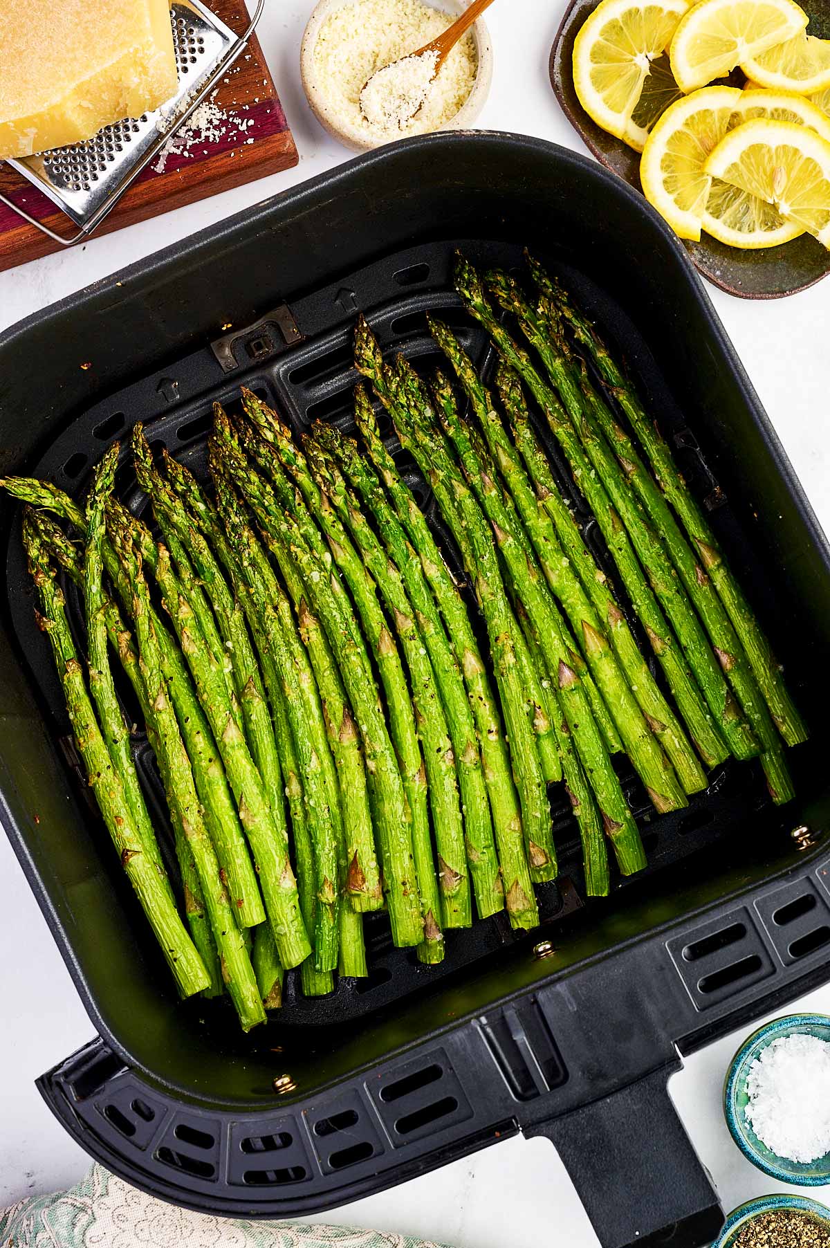 Air fryer basket filled with air fried asparagus stalks.