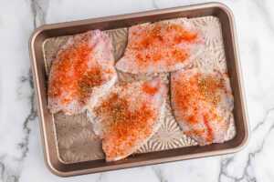 Seasoned tilapia on sheet pan.