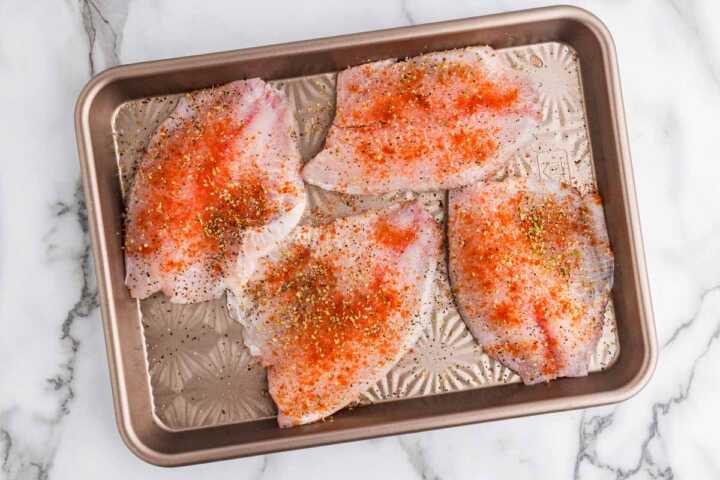Seasoned tilapia on sheet pan.