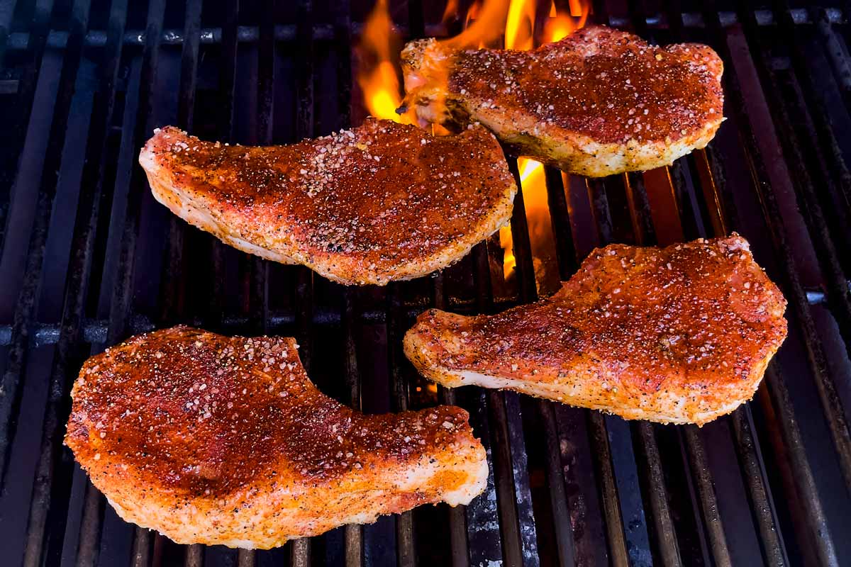Searing pork chops on a charcoal grill over direct heat.