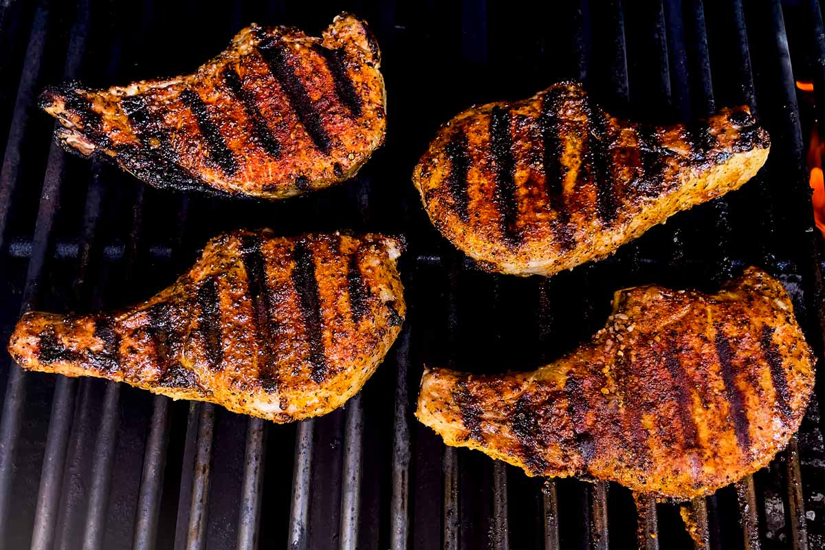 Grilled pork chops on a charcoal grill.