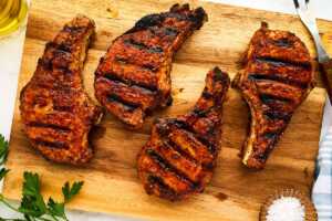 Grilled pork chops resting on a wooden cutting board.