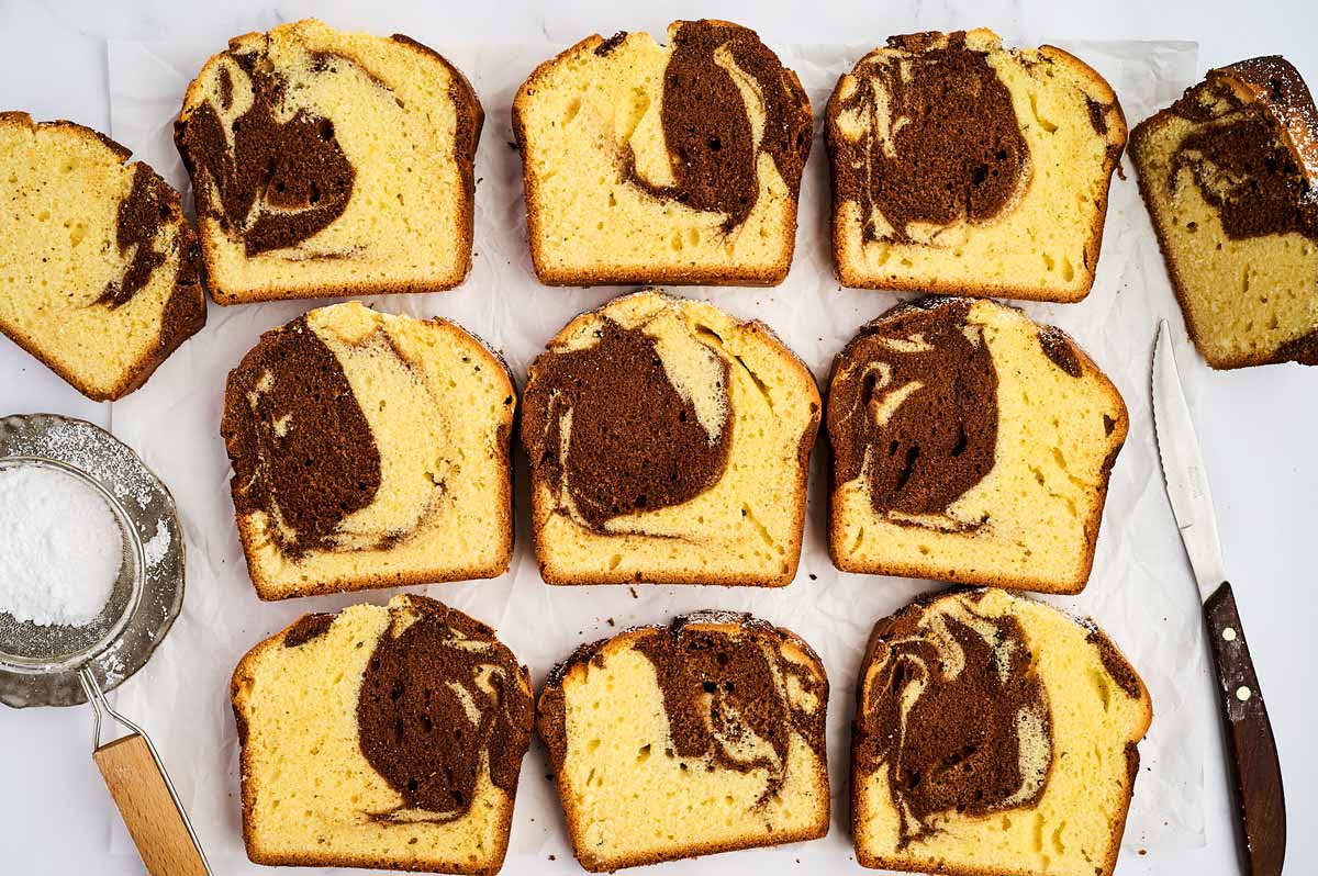 Slices of marble loaf cake on a piece of baking parchment.