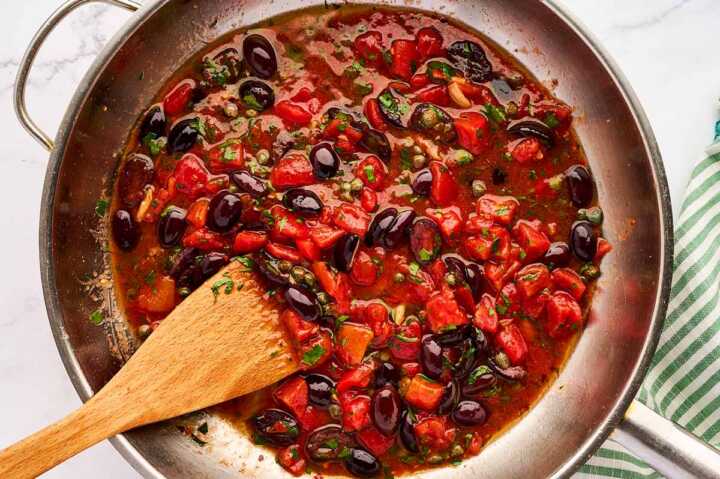 Sautéed ingredients for pasta puttanesca in skillet.