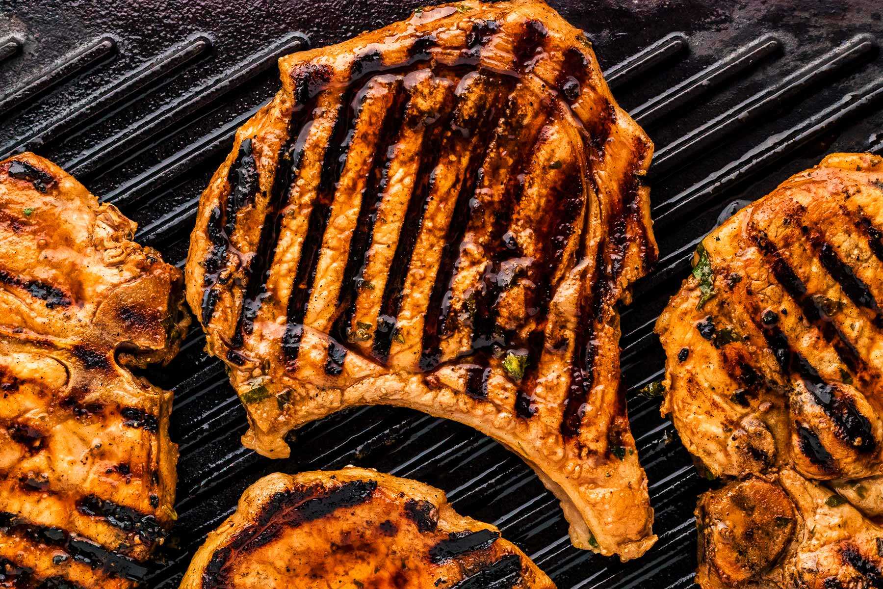 Grilled marinated pork chops on grill grates.