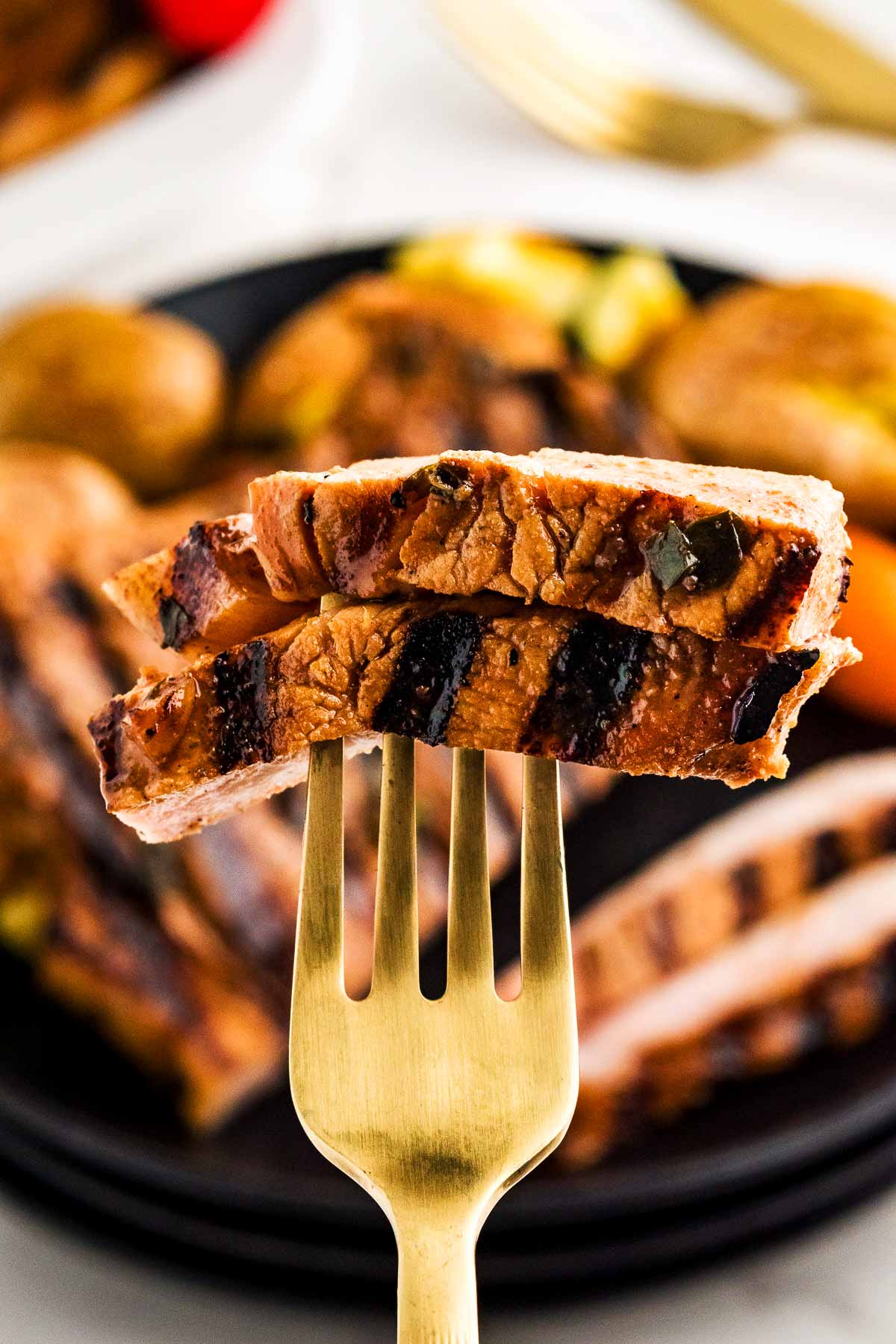 Fork picking up two slices of marinated pork chop.