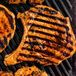 Grilled marinated pork chops on grill grates.